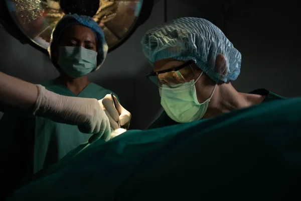 Asian Professional surgeons team performing surgery in the operating room, surgeon, Assistants, and Nurses Performing Surgery on a Patient, health care cancer and disease treatment concept