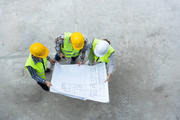 Top view of Asian engineer or Young Female Architect put on a helmet for safety and talk with a contractor on a construction building factory project, Concept of Teamwork, Leadership concept.