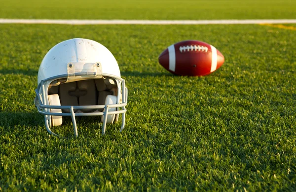 Voetbal helm en bal op het veld — Stockfoto