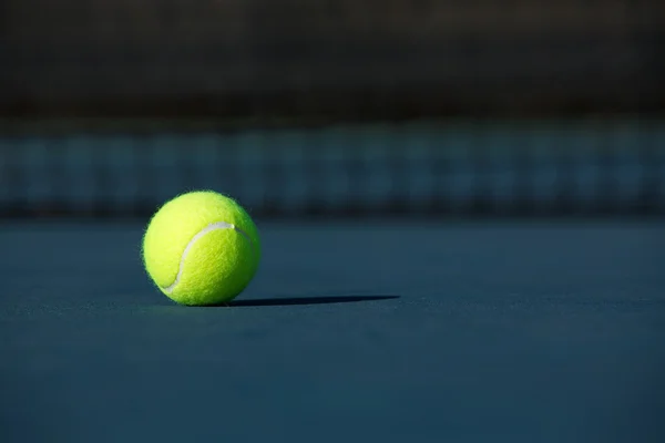 Теннисный мяч на синем корте — стоковое фото