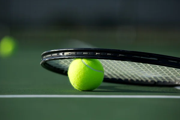 Pelota de tenis y raqueta en la cancha — Foto de Stock