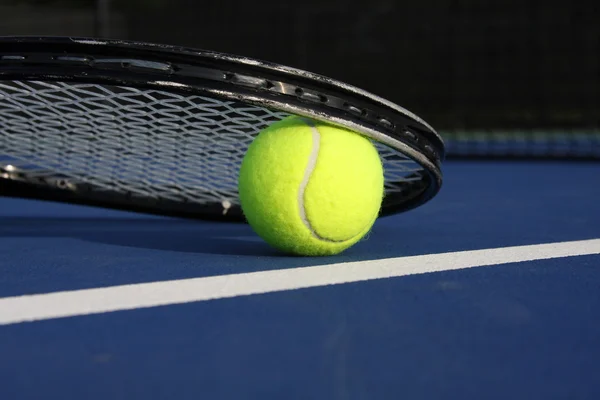 Pelota de tenis y raqueta en la cancha — Foto de Stock