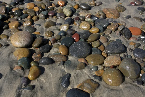 Soepele strand stenen op het zand — Stockfoto