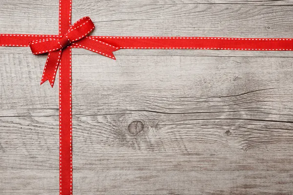 Красная лента и лук на деревянном фоне — стоковое фото