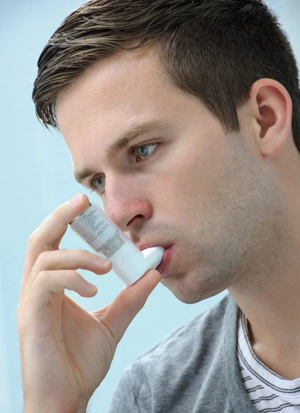 Hombre joven usando un inhalador de asma — Foto de Stock