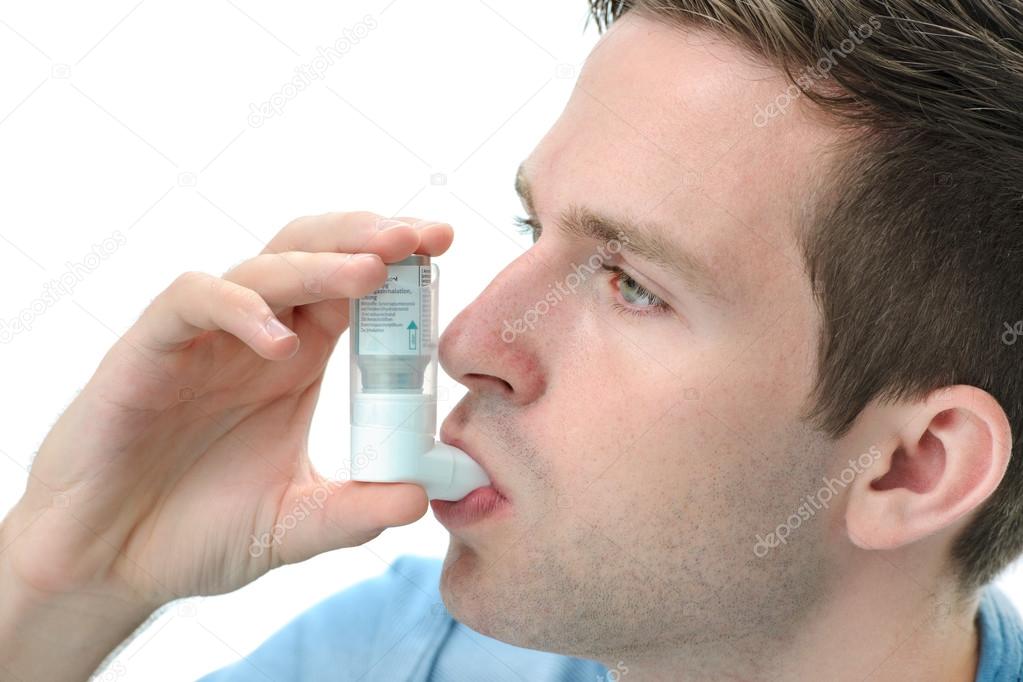 Young man using an asthma inhaler