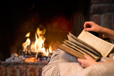 reading book by fireplace