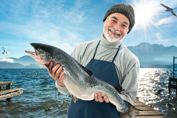 Фишер держит большую рыбу из атлантического лосося
