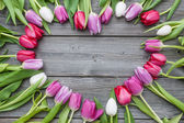 rám z čerstvých tulipánů na staré dřevěné pozadí