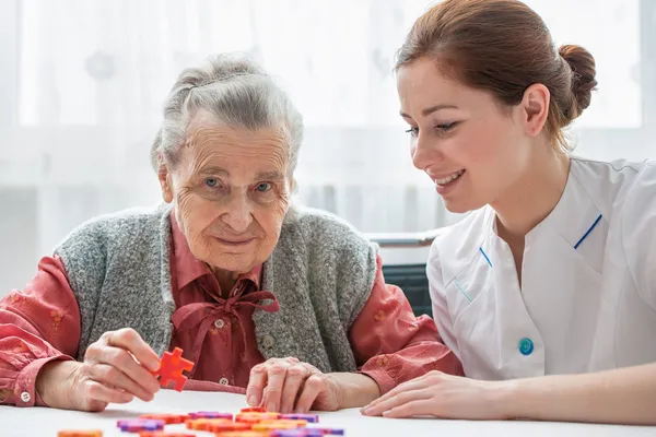 Senior vrouw met haar ouderenzorg verpleegster — Stockfoto