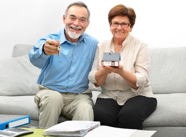 Happy senior couple holding a small house clipart