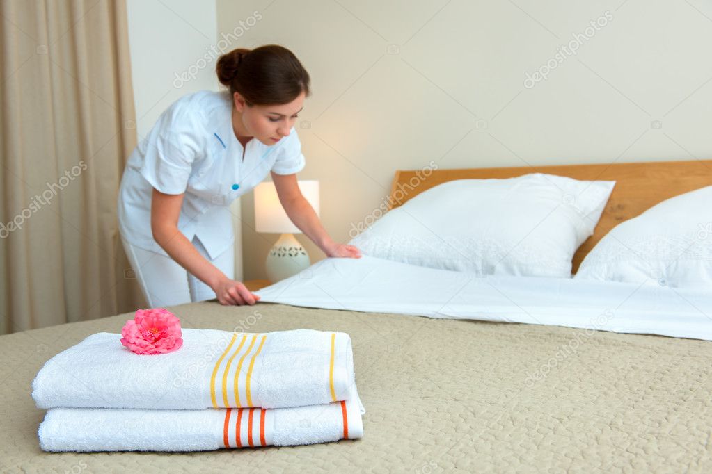 Maid making bed in hotel room Stock Photo by ©alexraths 51407189