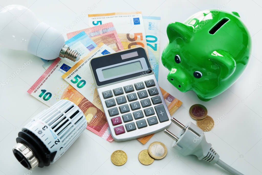 Energy cost, saving energy concept. Piggy bank, calculator and money, plug, bulb and radiator thermostat on white background