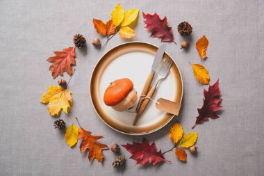 Şükran Günü sonbahar sofrası çatal bıçak takımı ve renkli dökülen yapraklar ve balkabağı.