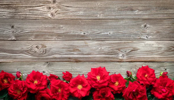 テキスト用のコピースペースを持つ素朴な木製のボード上の赤いバラ バレンタインデーなどの休日の背景 — ストック写真