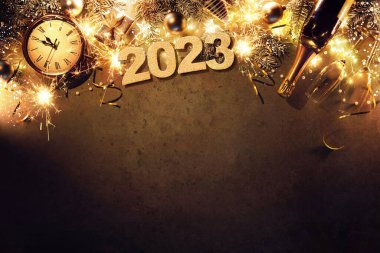 New Years Eve 2023 holiday background with fir branches, clock, christmas balls, champagne bottle, gift box and lights on dark board
