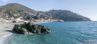 Bonassola 'daki kumsalda kayalık uçurum manzarası ve parlak kış ışığında çekilen yeşil tepe, La Spezia, Liguria, İtalya