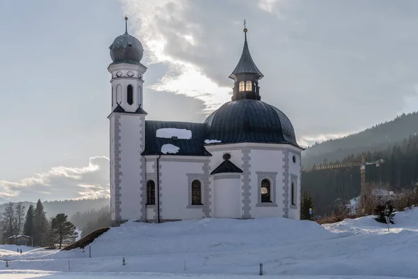 在奥地利蒂罗尔的Seefeld 城市景观 风景如画的巴洛克西克尔教堂 在雪地上被雪覆盖 充满了旅游的杂耍 在明亮的冬光中拍摄 — 图库照片
