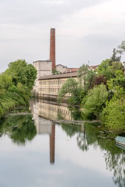 Adda Nehri suyuna yansıyan büyük sanayi binasının görüntüsü, Fara Gera Adda, Bergamo, Lombardy, Ital 'da açık bulutlu bir ışıkla çekildi.