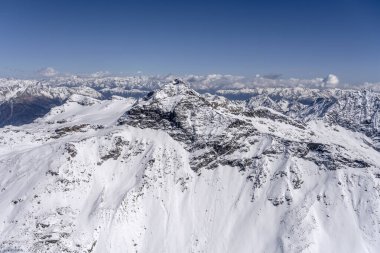 Scalino tepesindeki küçük bir uçaktan havadan çekilen karlı yamaçlardan yükselen karlı karlar altında kuzeybatıdan çekilen parlak bahar ışığı, Sondrio, Ital
