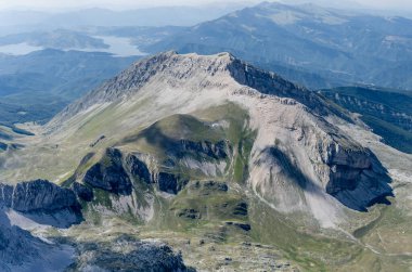 aerial shot, from a small plane, with barren crags of Corvo peak in Gran Sasso range with Campotosto lake in background, shot from south-west in bright summer light, Apennines, L'Aquila, Abruzzo,  Italy