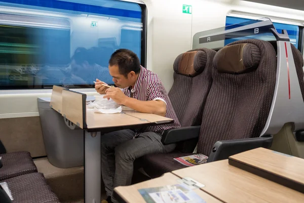 Asiático homem jantando no moderno italiano trem, circa outubro 2013 — Fotografia de Stock