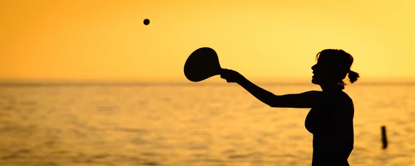 Mulher jogando bola de remo na praia — Fotografia de Stock