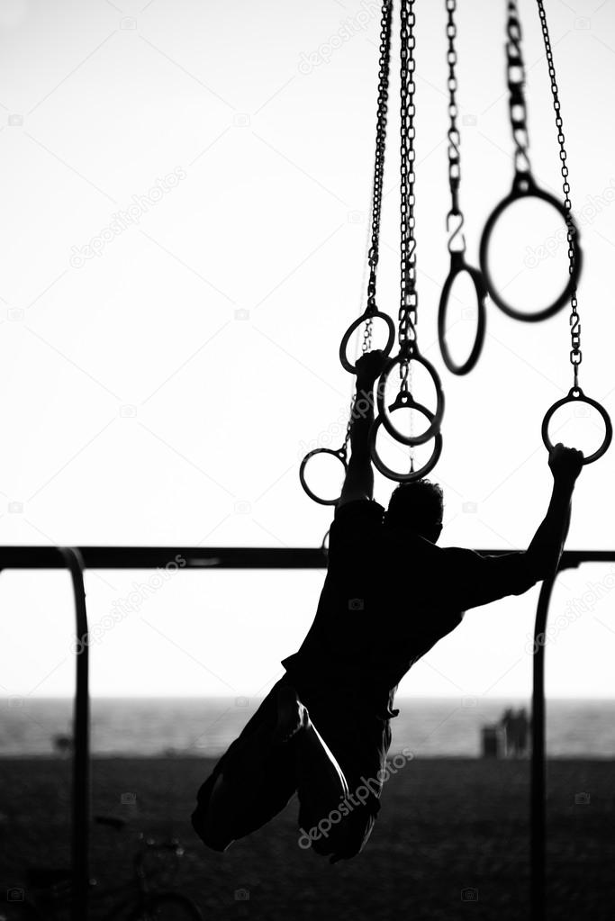Silhouette of a person swinging on rings