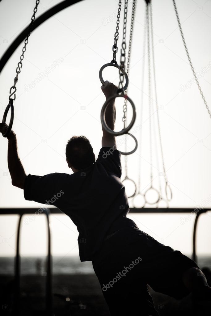 Silhouette of a person swinging on rings