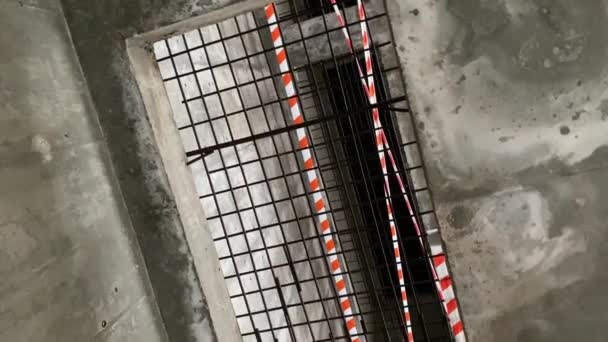 Una gran abertura rectangular en el suelo de hormigón está cubierto con una rejilla de hierro y blindado con cinta protectora — Vídeo de stock