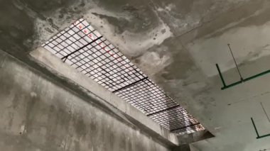 Beton zeminde büyük bir dikdörtgen açıklık demir bir ızgarayla kaplı ve koruyucu bantla korunuyor.