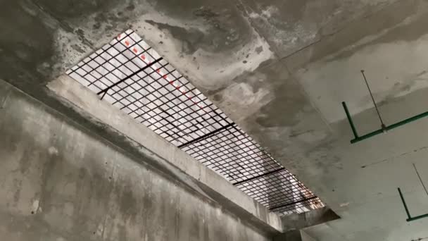 En stor rektangulär öppning i betonggolvet är täckt med ett järngaller och skärmat med skyddstejp — Stockvideo