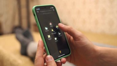 Kiev, Ukrayna - 16 Kasım 2021: Eller glovo dağıtım uygulamasındaki bir katalogdan restoran seçiyor. Yemek servisi. Evden gelen iPhone 11 aracılığıyla sipariş kanepede yatıyordu.