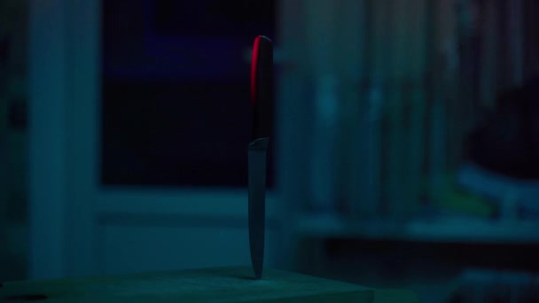 Un couteau dans un tableau de cuisine sur fond de lumières clignotantes de la police. Arme de crime en rouge vif et bleu clignotant — Video