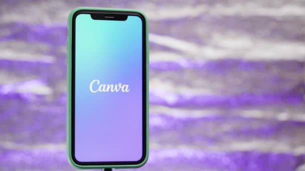 Kyjev, Ukrajina - 16. listopadu2021: Canva app otevírá detailní záběr na iPhone11. Pozadí se třpytí v různých barvách — Stock video