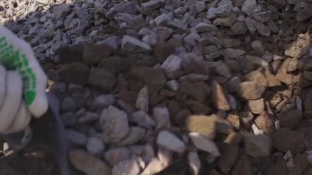 Primer plano de un hombre paleando una pala llena de construcción de piedra triturada en cámara lenta — Vídeos de Stock