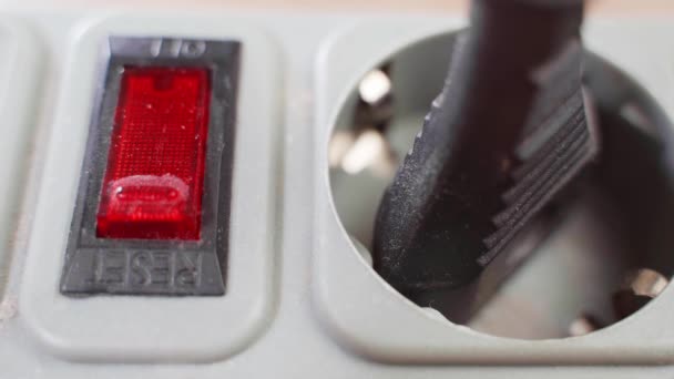 Prst stiskne spínač na prodlužovacím kabelu s červenou LED zblízka. Zástrčka je vložena do zásuvky — Stock video