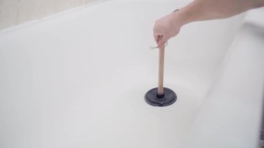 Banyodaki tıkanıklığı lavabo pompasıyla çıkarmaya çalışıyorum. Bir el akmayan suyla dolu bir küvette pompa kullanır.