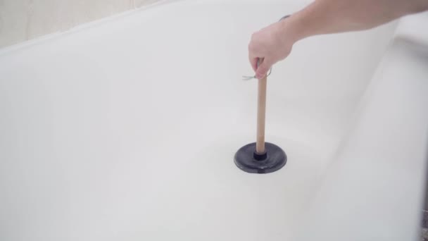 흡입기를 사용하여 화장실 아래 파이프의 막힌 곳을 제거하려고 한다. 손은 물이 흐르지 않는 욕조에서 플런저를 사용 합니다. — 비디오