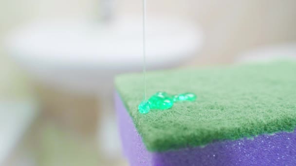 緑色の液体石鹸は、緑色と紫色のキッチンスポンジに適用されますクローズアップ — ストック動画