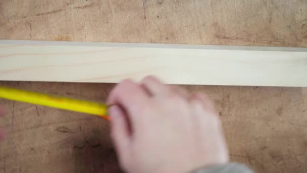 La mano mide la longitud de un bloque de madera con una cinta métrica de primer plano — Vídeo de stock