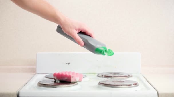 Hand gießt Waschmittel aus einer grauen Flasche auf einen Küchenherd — Stockvideo