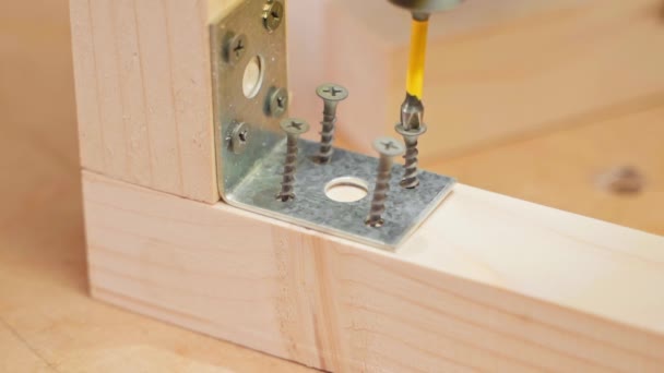 Śruba samogwintująca dokręca śrubokręt elektryczny. Mocowanie żelaznego narożnika do drewnianych belek — Wideo stockowe