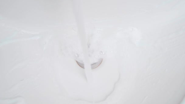 Afwassen van het wasmiddel van het oppervlak van de gootsteen met water. Wassen van de wastafel met een spons close-up — Stockvideo