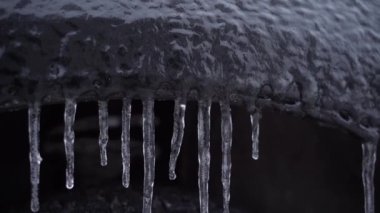 Sarkık buz saçakları olan siyah bir arabanın çamurluğu.