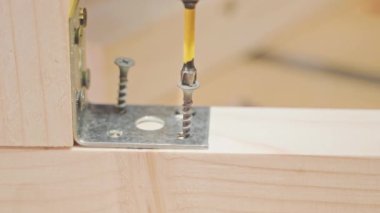 Tornavidayla çapraz kafanın yakın çekimi metal bir köşeyi sağlamlaştırmak için tahta bir çubuğa vidalanır.