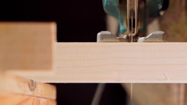 A man saws a wooden beam with a jigsaw close-up — Vídeo de Stock