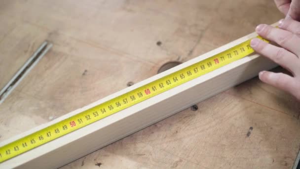 Hands measure the distance with a construction tape measure with a ruler of a wooden bar and mark with a pencil — 图库视频影像