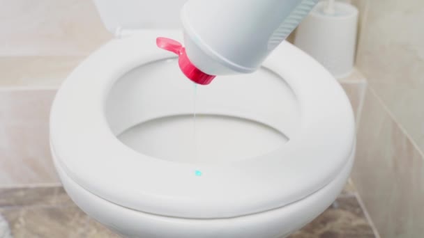 Vloeibare zeep van een heldere kleur wordt gegoten uit een plastic fles op de rand van het toilet — Stockvideo
