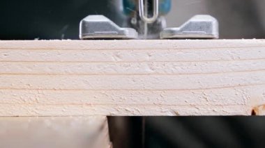 Jigsaw sawing a pine log close-up, front view